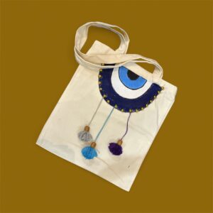 حقيبة كتف قابلة للارتداء اليومي مصنوعة من القماش عالية الجودة بتصميم فني يدوي برسمة عين زرقاء لامعة تجعل الحقيبة قطعة مميزة